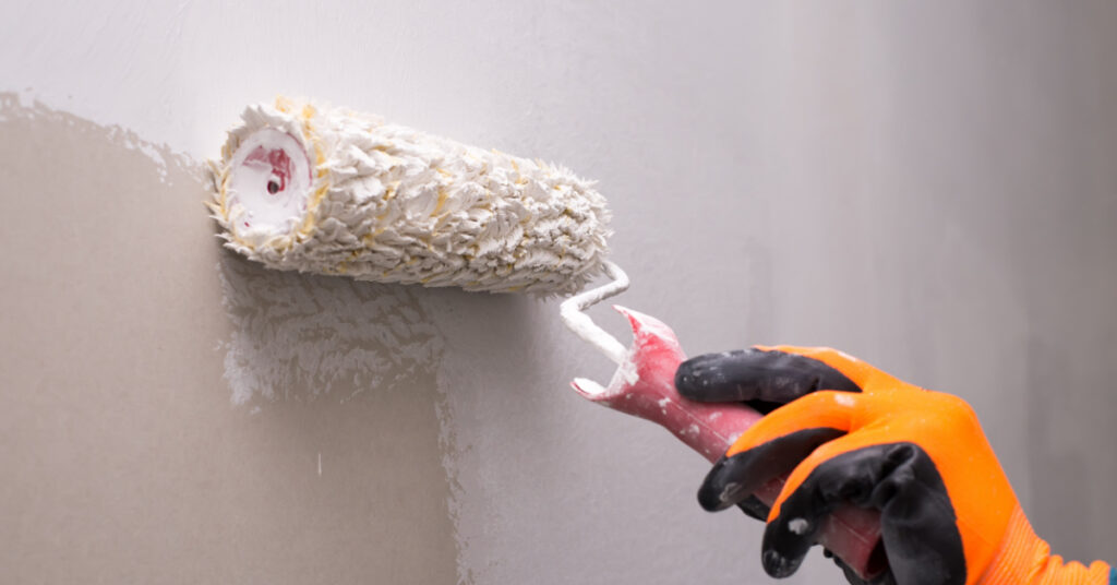image of a painter applying a coat to a wall with a paint roller for this article which describes the different uses of surfactants in the CASE industry